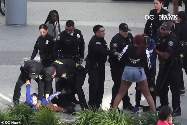 The two women are arrested by the police, one of them being pinned to the ground.