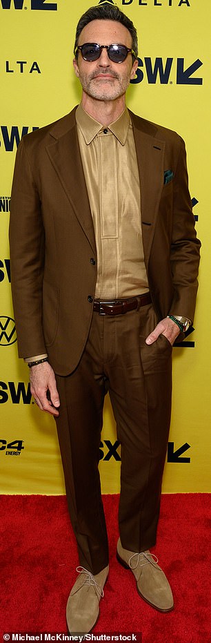 Handsome hunk Reid Scott caused a stir in a screaming gold top under his brown suit