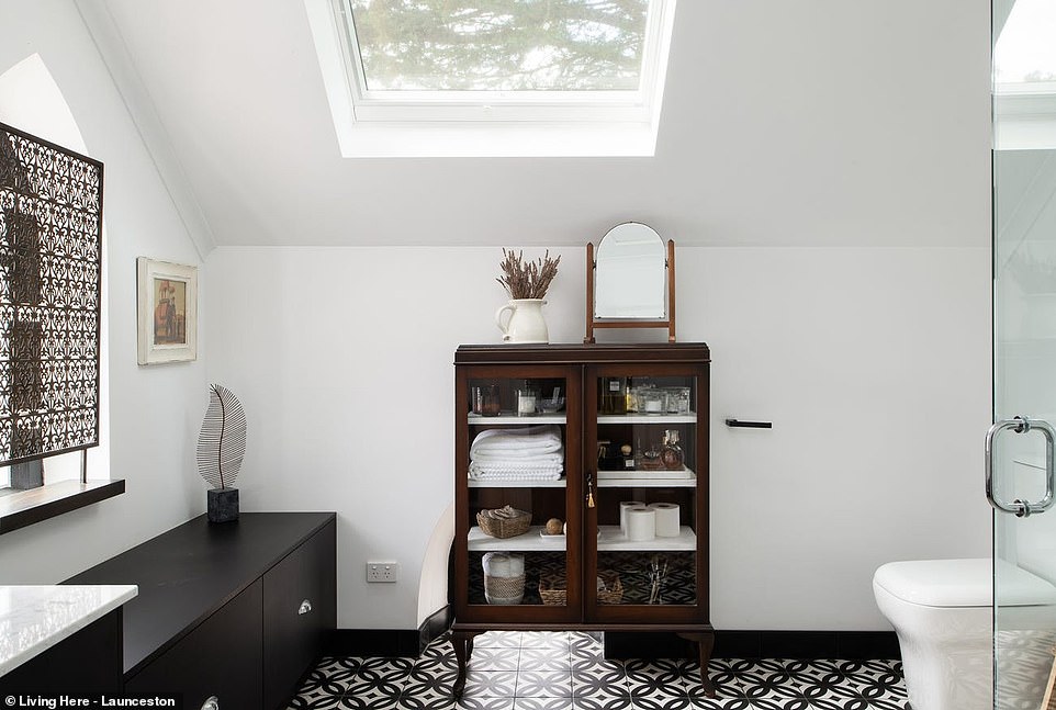 The home's unique monochrome theme continues in the bathroom with fun patterned tiles, crisp white walls, marble countertops and black wood joinery.