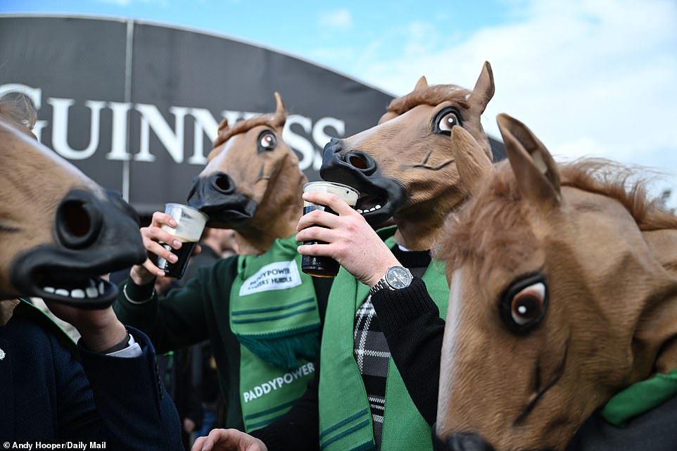 Fans get into the Cheltenham mood as they sip their pints of Guinness while wearing a horse mask and Paddy Power scarf
