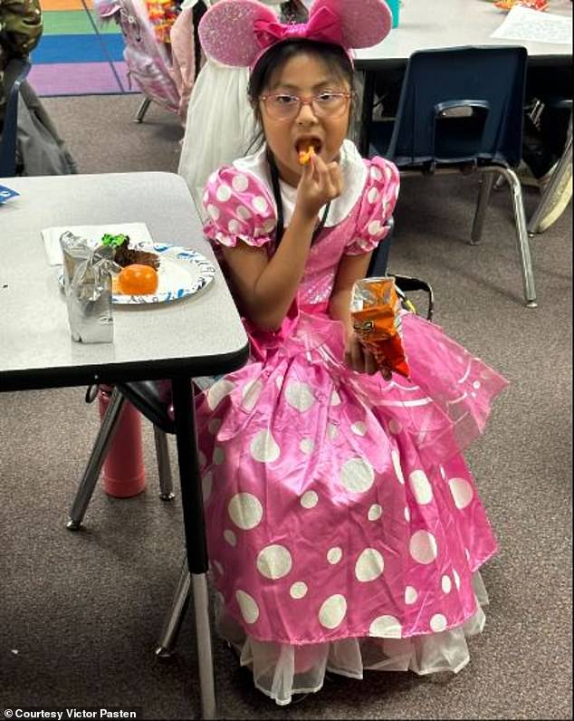 The second grader is seen having a snack at her school, dressed as Minnie Mouse.