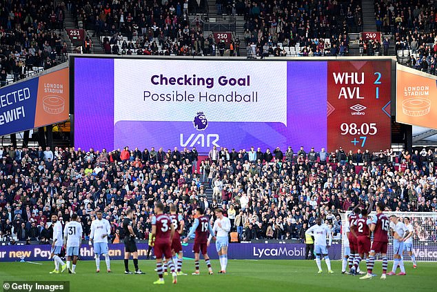 The players and more than 62,000 paying spectators in the London Stadium have no idea what is happening as VAR Tony Harrington checks several replays.