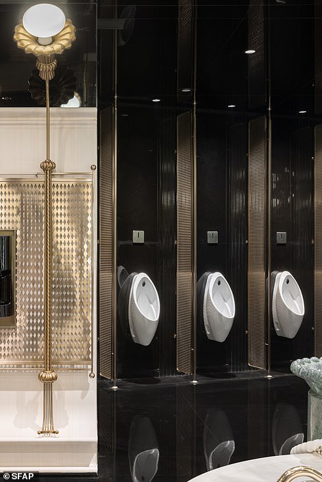 The urinals are separated by champagne-gold grilles