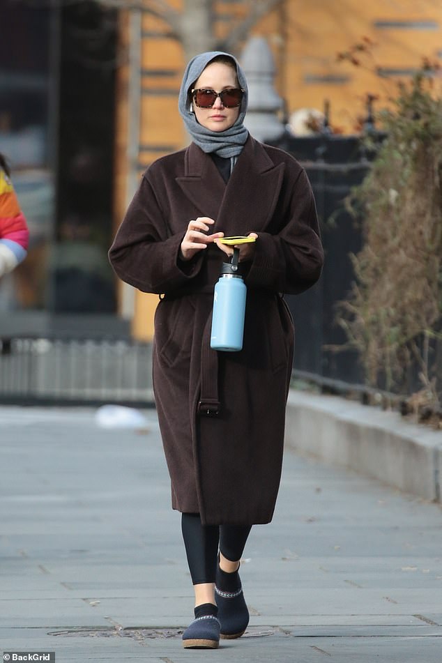 The Hunger Games star, 33, dressed in a gray scarf and a chic oversized brown coat, with a belt cinching her waist