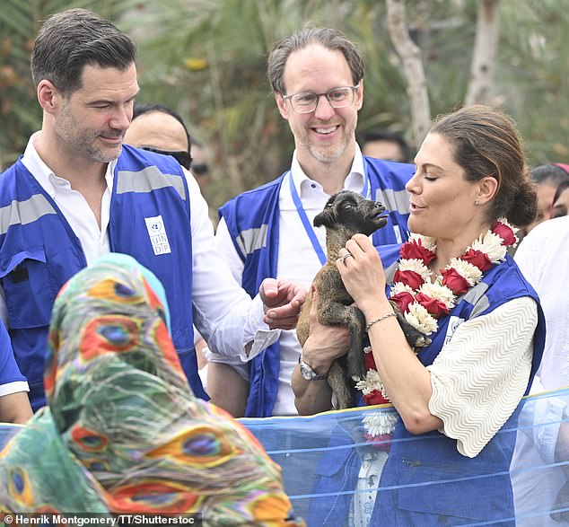 Victoria opted for natural makeup and her brunette locks were pulled back into a casual bun as she smiled for the cameras while holding a little goat.