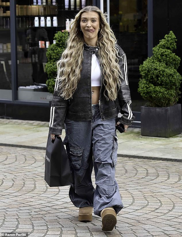 The reality star, 22, showed off her incredible figure in a white crop top and low-rise blue cargo pants as she changed her look with long blonde extensions at Sands Hairdressers.