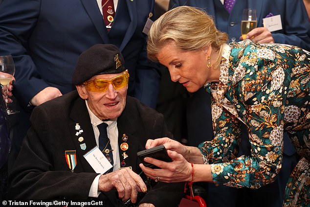 The Duchess interacted with Korean War veteran Roger Baker (pictured left) and appeared to glance at his phone.
