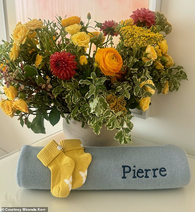 She shared an image of a blue baby blanket embroidered with her newborn's name, along with an adorable pair of yellow knit baby booties.