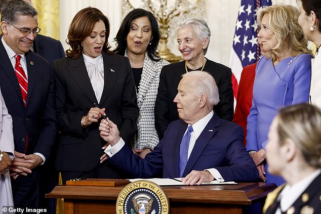 US President Joe Biden offers US Vice President Kamala Harris a pen after signing an executive order at the White House