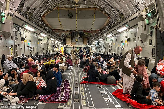 Afghans sit aboard a U.S. military plane to leave Afghanistan, at the Kabul military airport, August 19, 2021, after the Taliban military takeover of Afghanistan.