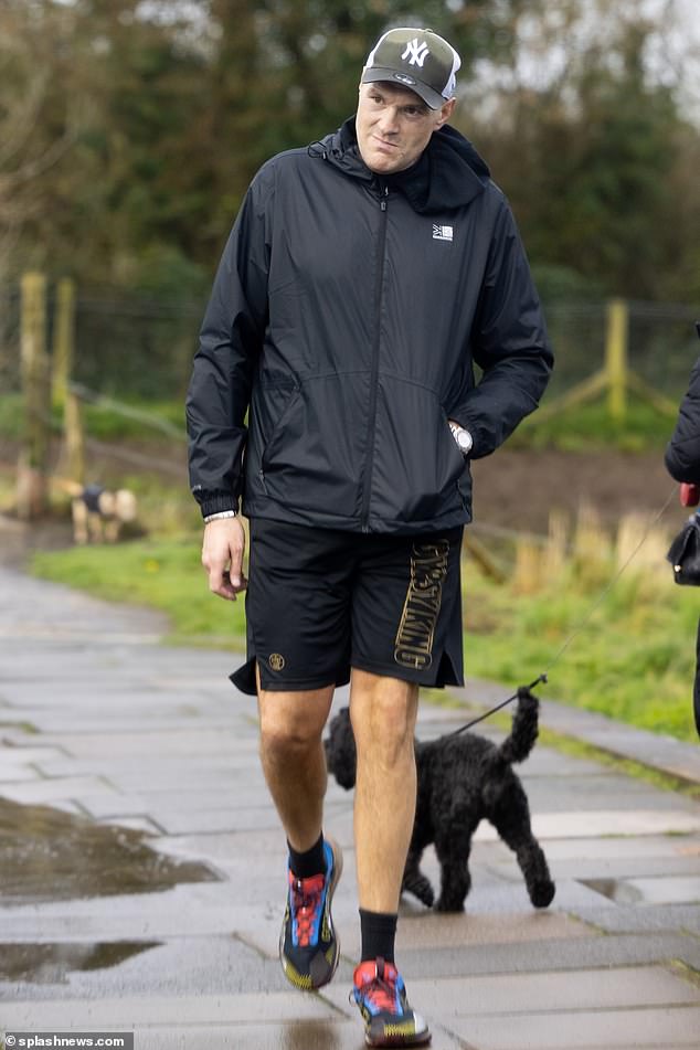 The athlete cut a relaxed figure in a black raincoat which he teamed with matching shorts and a green cap.