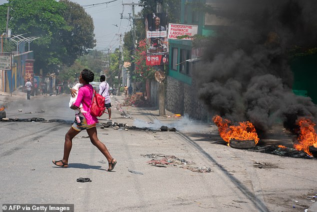 A woman hugs her baby and runs as gunshots ring out across Port-au-Prince, as at least 80 percent of the capital is in the hands of gangs who are turning to the city's wealthy neighborhoods. city.