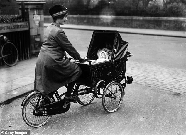 A woman pushing her baby in a specially adapted pram attached to her bicycle in Brixton, south London, 1926
