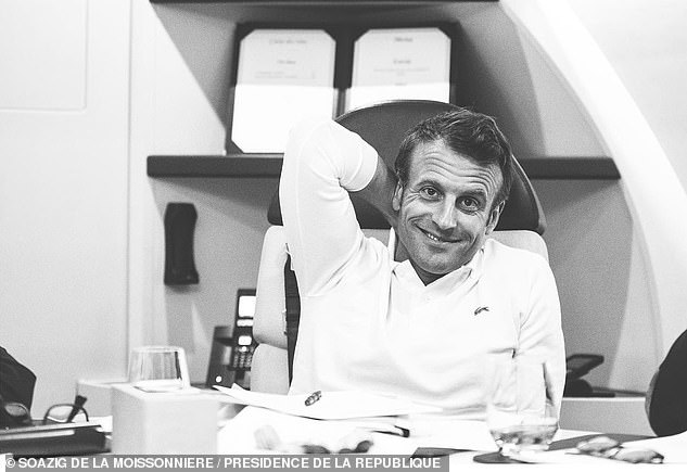 French President Emmanuel Macron is pictured smiling at his desk in another official photo