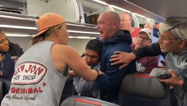 The other passenger, a white man wearing a blue hoodie, decided to intervene and escort her off the plane.