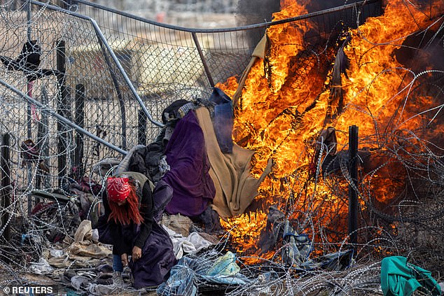 A migrant checks her bag after members of the Texas National Guard burned clothing used by migrants to break barbed wire and a fence to enter the United States and surrender.