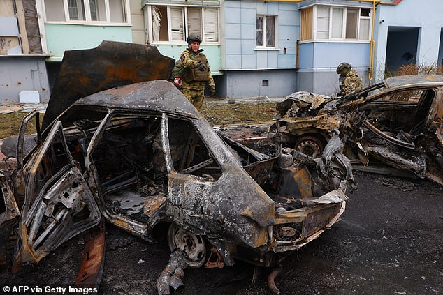 Self-defense unit volunteers near burned cars in a residential area of ​​the city of Belgorod after new air attacks on March 22, 2024