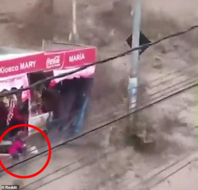 A child was seen falling to the ground and then being picked up by an adult moments after water surged over a reservoir wall during a rainstorm in La Paz, Bolivia on Wednesday