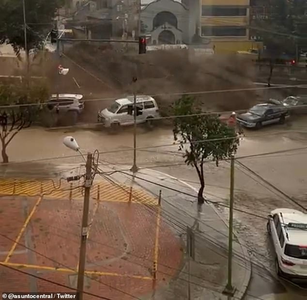 Floodwaters spilled over the reservoir wall in La Paz as heavy rain hit the Bolivian capital on Wednesday, sending vehicles sliding onto a street