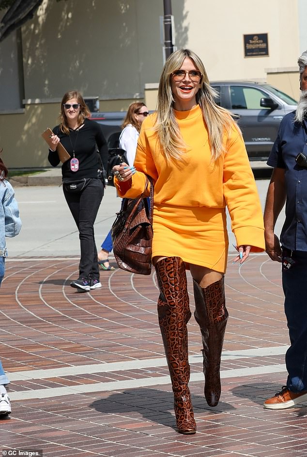 Her previous outfit consisted of a baggy orange long-sleeved top, paired with a form-fitting mini skirt in the same color