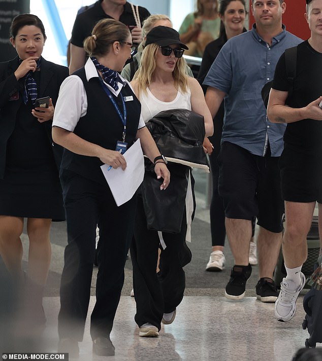 The singer hid her flawless complexion behind large sunglasses and a black cap as she walked through the airport.