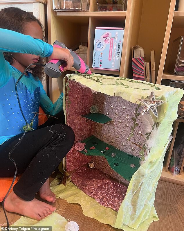 The model supervised her daughter as she applied some hot glue to a diorama.
