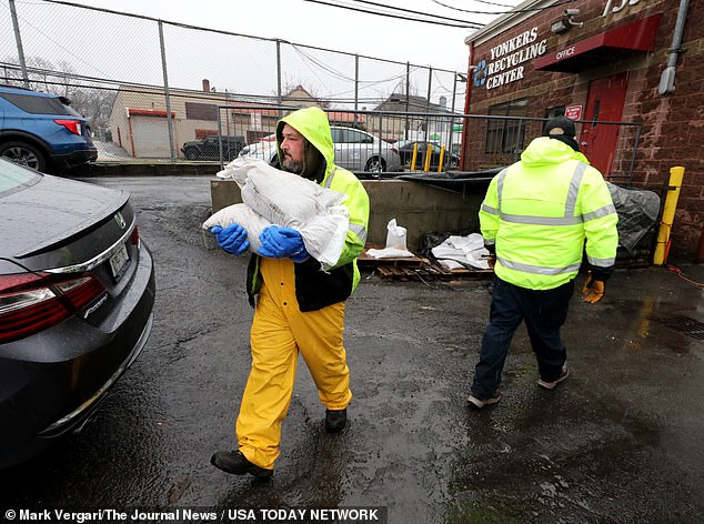 Yonkers Department of Public Works employees carry sandbags to waiting Yonkers residents as they distribute them at the Yonkers Recycling Center.