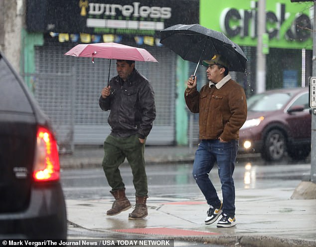 Pedestrians along South Broadway in Yonkers take shelter from the rain.  The heavy rain that began Friday afternoon is attributed to the merger of two storm systems, one from the north and one from the south.