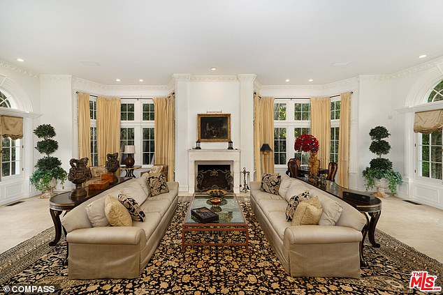 A spacious living room with fireplace and French doors leading to the garden.
