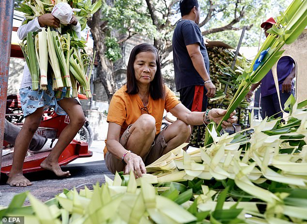 A woman buys palm leaves in front of a Catholic church on the eve of Palm Sunday in the city of Las Piñas, Philippines.