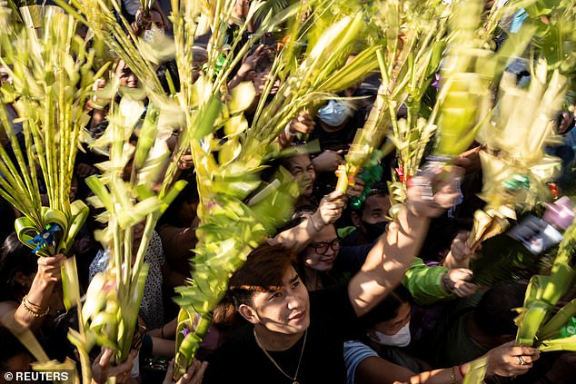 Filipino Catholics raising their palm leaves to receive blessings during a Palm Sunday mass at the Antipolo Cathedral