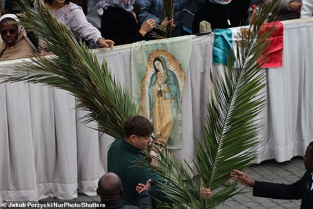 A man carries palms before Palm Sunday mass in St. Peter's Square at the Vatican.
