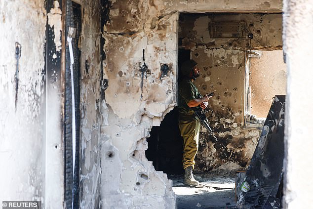 A soldier watches from a bullet-riddled house following the deadly Oct. 7 attack by Hamas gunmen from the Gaza Strip on the Kfar Aza kibbutz.