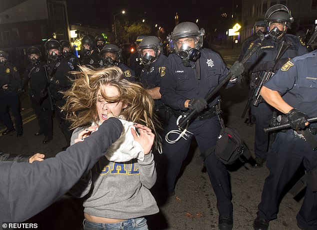 A protester near Berkeley flees as police officers try to disperse a crowd made up mainly of students during a protest against police violence in the United States.