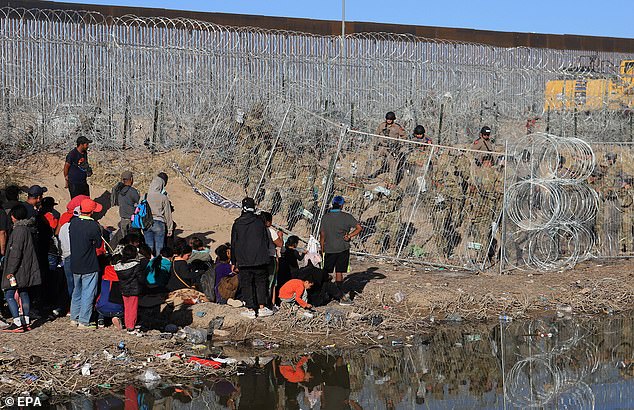 U.S. National Guard personnel reinforce a concertina wire-covered fence near migrants at the border with Mexico on March 23, 2024