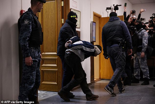 A man suspected of involvement in the concert hall attack that killed 137 people, the deadliest attack in Europe claimed by the Islamic State jihadist group, is escorted by Russian law enforcement officers