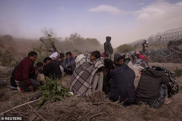 Migrants huddle in the dry bed of the Grand River near El Paso, Texas.