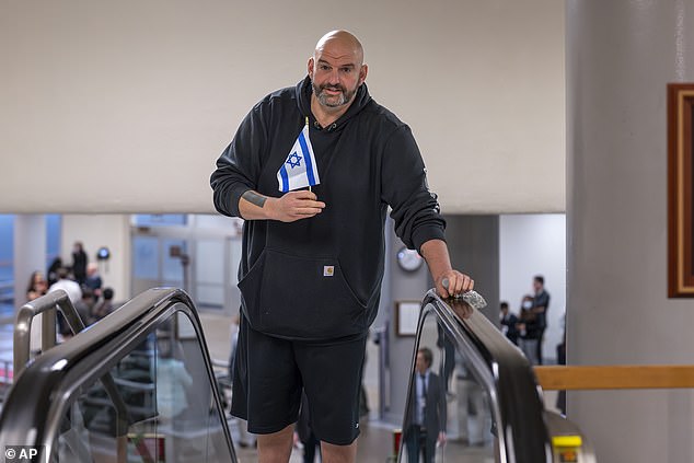 Sen. John Fetterman, D-Pa., holds a small Israeli flag as he heads to the chamber to vote.