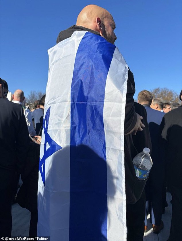 John Fetterman drapes the Israeli flag over his shoulders at a March for Israel rally