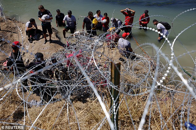 Migrants wait behind barbed wire after crossing the Rio Grande into the United States in Eagle Pass, Texas, USA, on September 28.