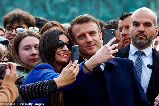 French President Emmanuel Macron (center) poses with the public for a selfie after a ceremony to seal the right to abortion in the French constitution, on International Women's Day, at Place Vendome in Paris, on the 8th March 2024.