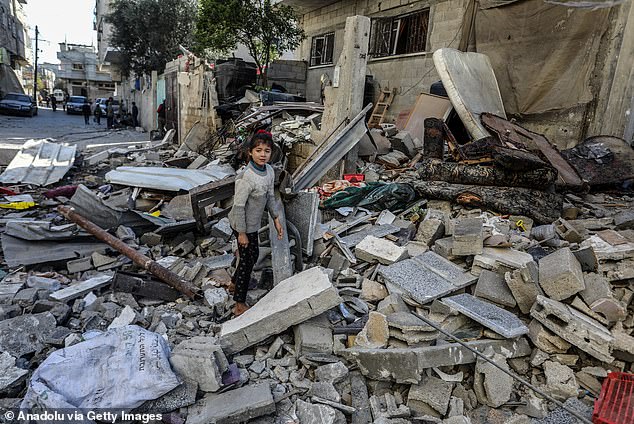 Palestinians, including children, sift through the rubble and collect remaining belongings from the severely damaged building, part of which collapsed following an Israeli attack.