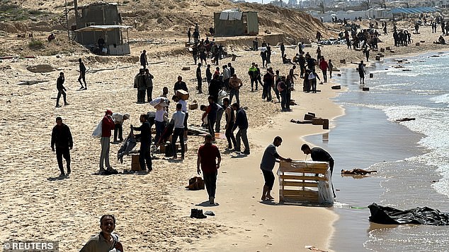 Palestinians gather on a beach while collecting aid dropped from a plane, in the midst of the current conflict between Israel and Hamas, in the northern Gaza Strip.