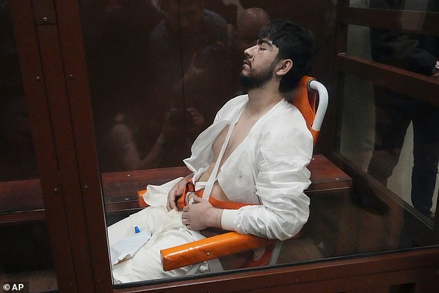 Mukhammadsobir Faizov, suspect in Friday's Crocus City Hall shooting, sits in a glass cage at the Basmanny District Court in Moscow, Russia, early Monday, March 25, 2024.