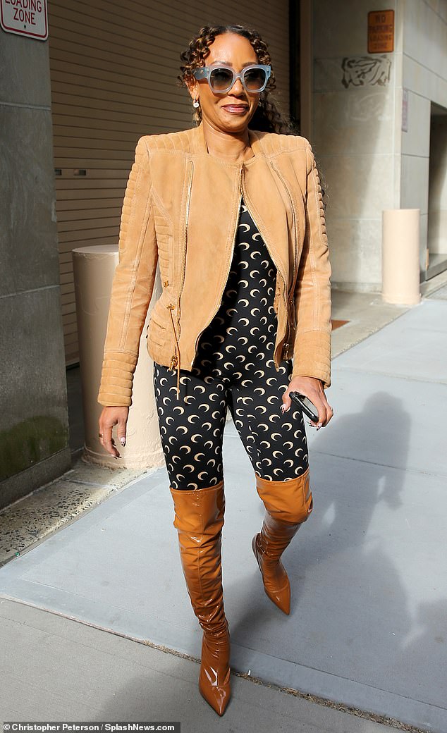 The star accessorized her look with a light brown suede jacket and wore long PVC boots over the catsuit.