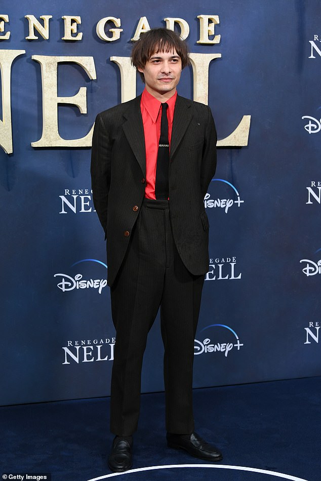 Frank Dillane arrived in an elegant black suit and a peculiar red shirt.