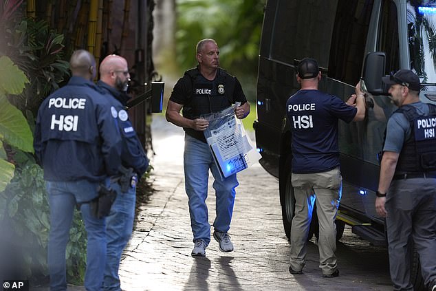 A law enforcement officer carries a bag of evidence to a van at Diddy's Miami home after the raid.