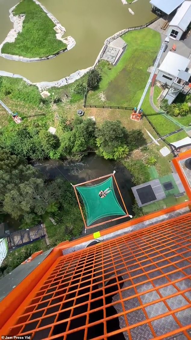 But there was a trampoline placed underneath to cushion the thrill seekers' fall (pictured: woman landing on a trampoline below)