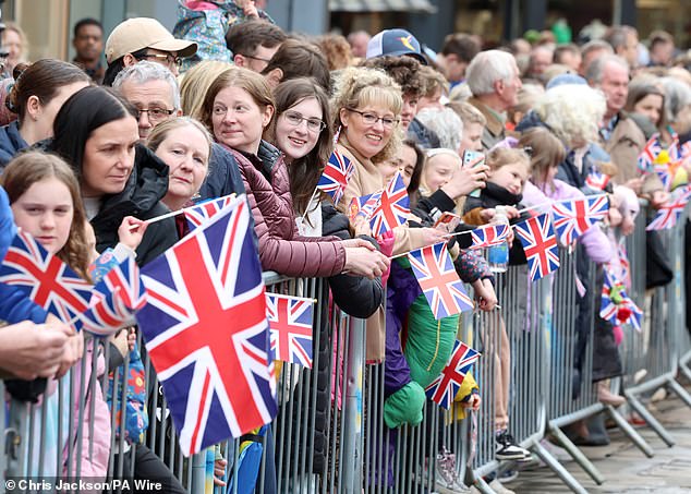 The public awaits the arrival of Queen Camilla for her visit to the farmers market in the square.