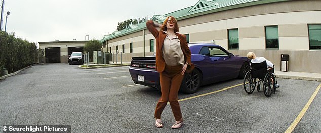 After leaving in a Dodge Challenger, a shot of Stone shows her standing near the car and making a move in a rust-colored pantsuit.